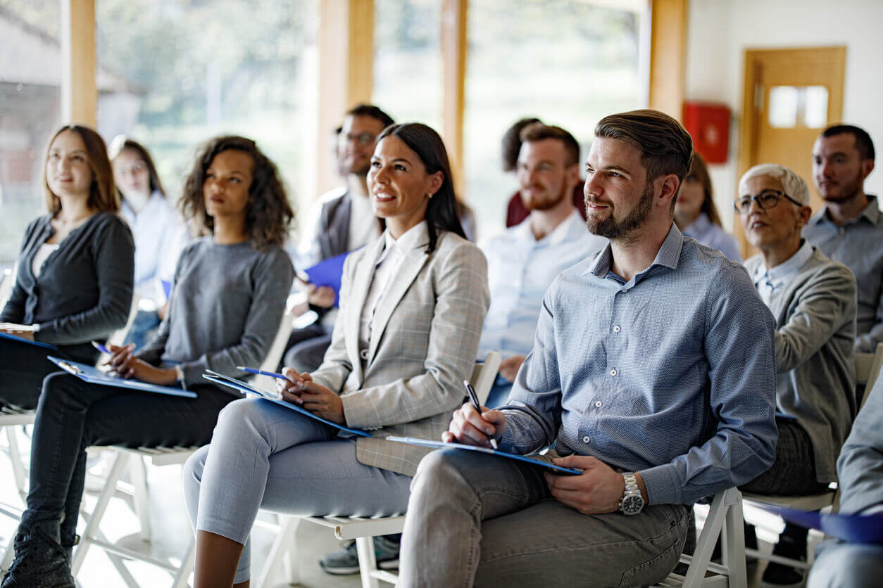 Colaboradores atentos e sorrindo durante eventos corporativos, representando estratégias de engajamento em ações internas da empresa.