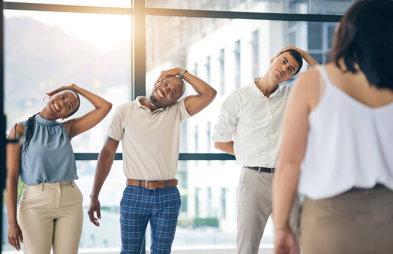 Colaboradores realizando alongamento guiado em ambiente corporativo, representando ações preventivas relacionadas à avaliação de riscos ocupacionais e promoção da saúde no trabalho.